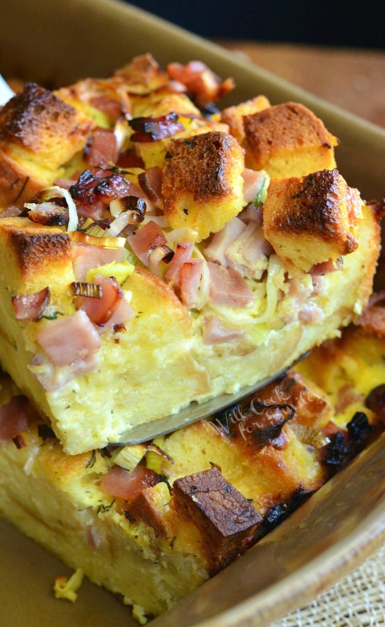 Ham Leek and Cheese Bread Pudding being lifted out of a baking pan with a spatula 