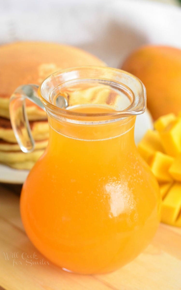 Homemade Mango Syrup in a glass with pancakes in the background 