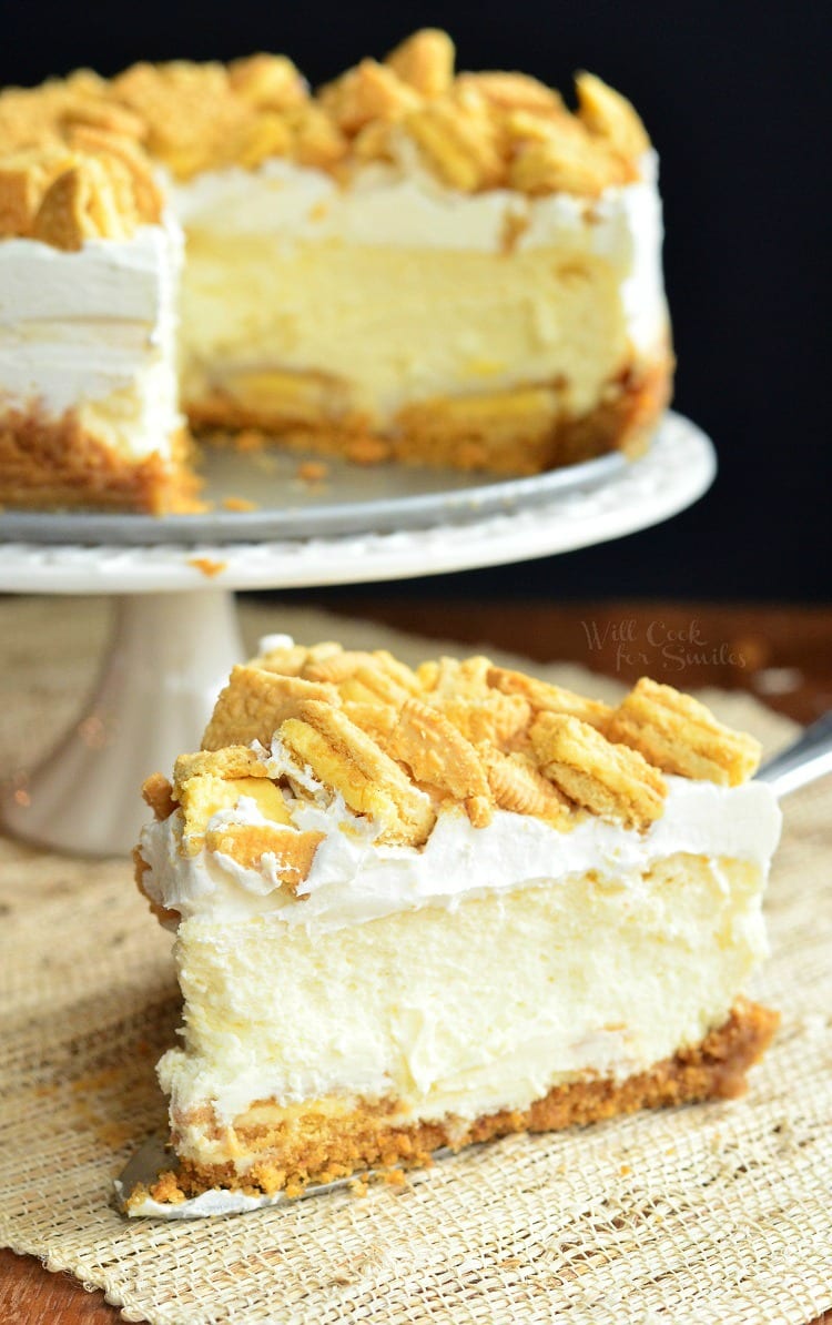 Lemon Oreo Cheesecake with crushed oreos on top on a cake pan with a slice below it on the table 