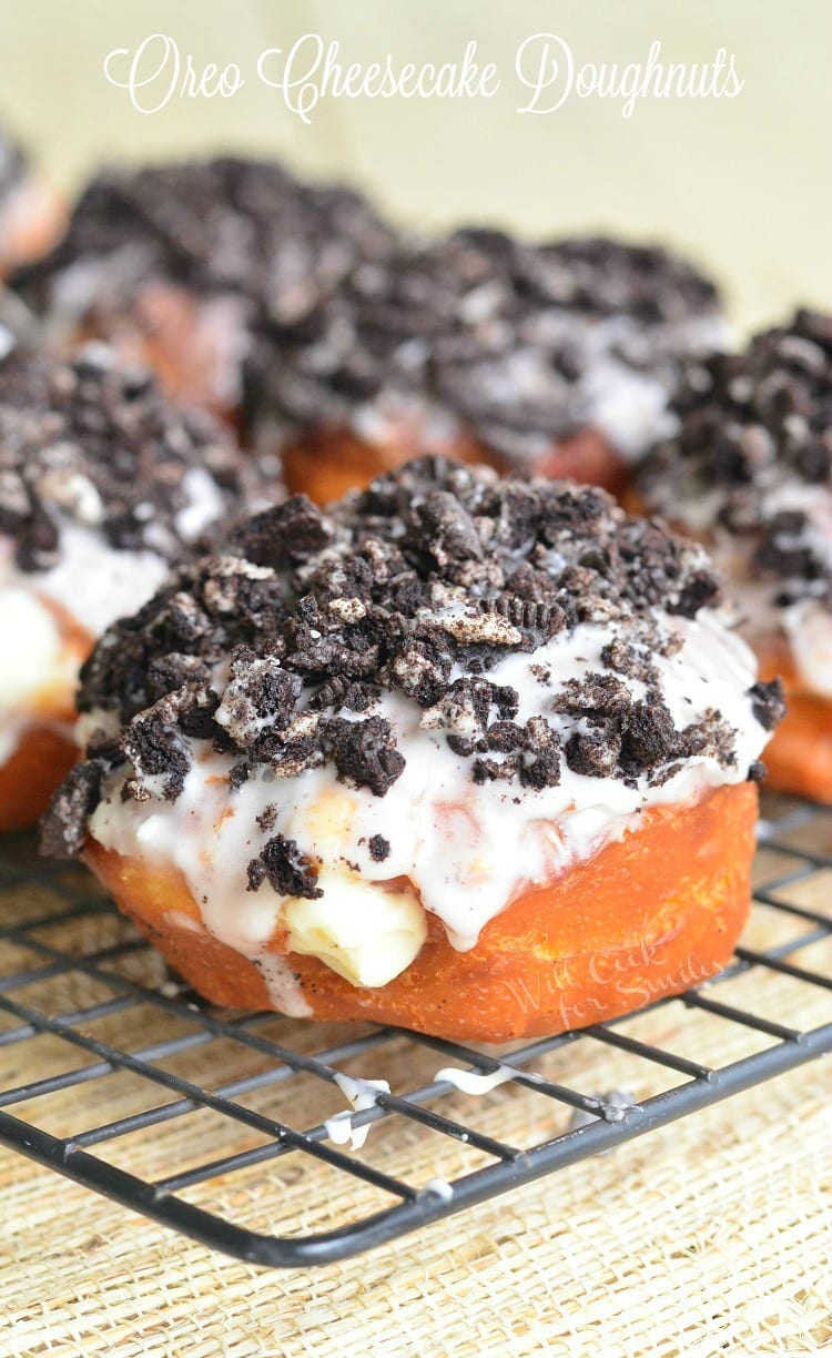 Oreo Cheesecake Doughnuts with crushed oreas on top on a cooling rack 