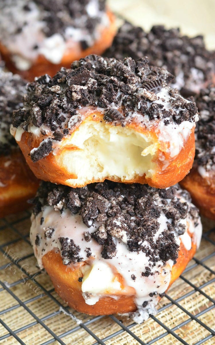 Oreo Cheesecake Doughnuts stacked on top of each other on a cooling rack