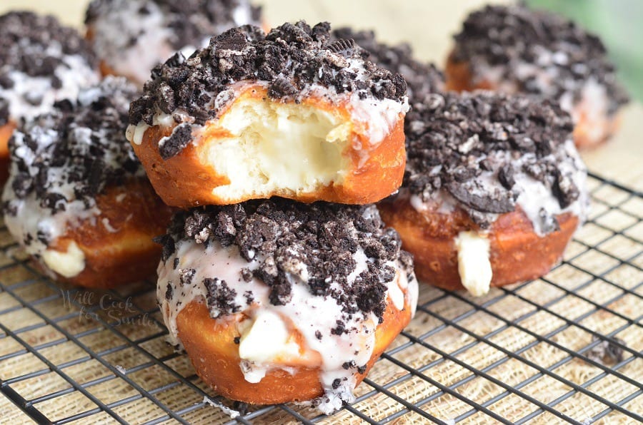 Oreo Cheesecake Doughnuts with crushed oreas on top on a cooling rack 