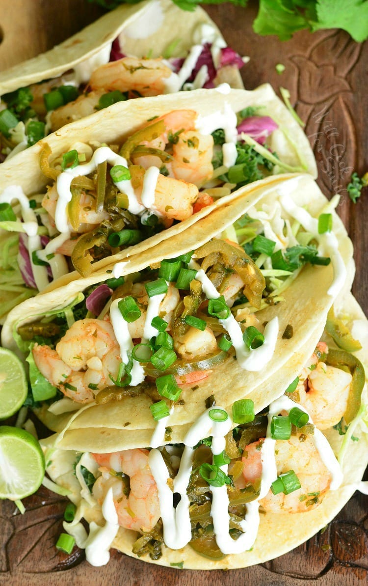 Top view of tequila Lime Shrimp Tacos with sour cream and green onions on top 