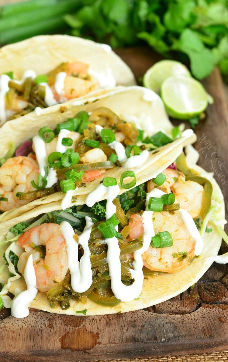 tequila lime shrimp tacos with sour cream drizzled on top on a cutting board 