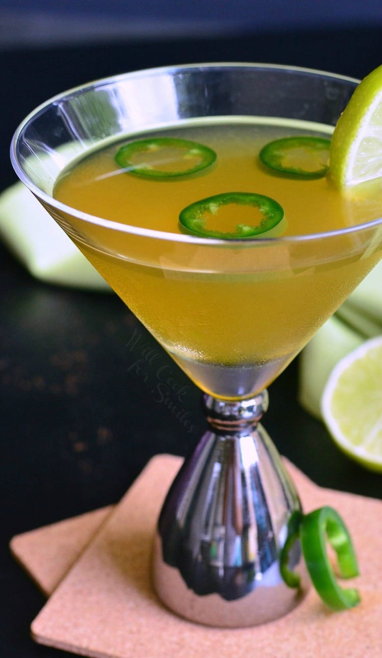 Jalapeno Margatini in a martini glass with 3 jalapenos and a lime 