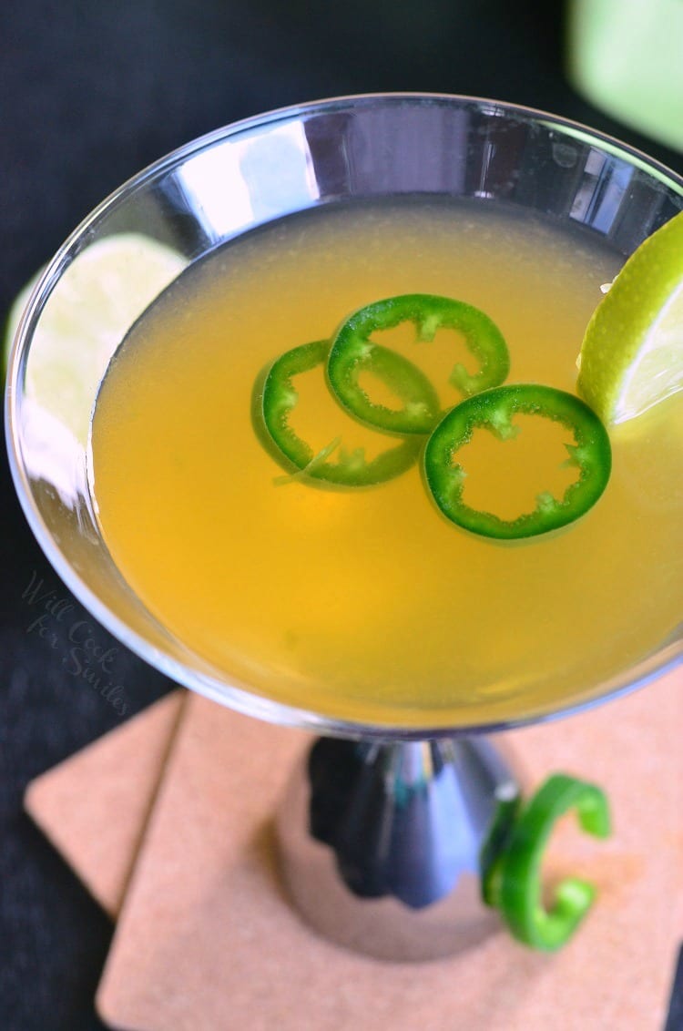 top view photo of Jalapeno Margatini in a martini glass with 3 jalapenos and a lime 