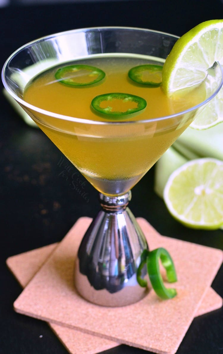 Jalapeno margarita in a martini glass with slices of Jalapeno on top and lime on the side for garnish 