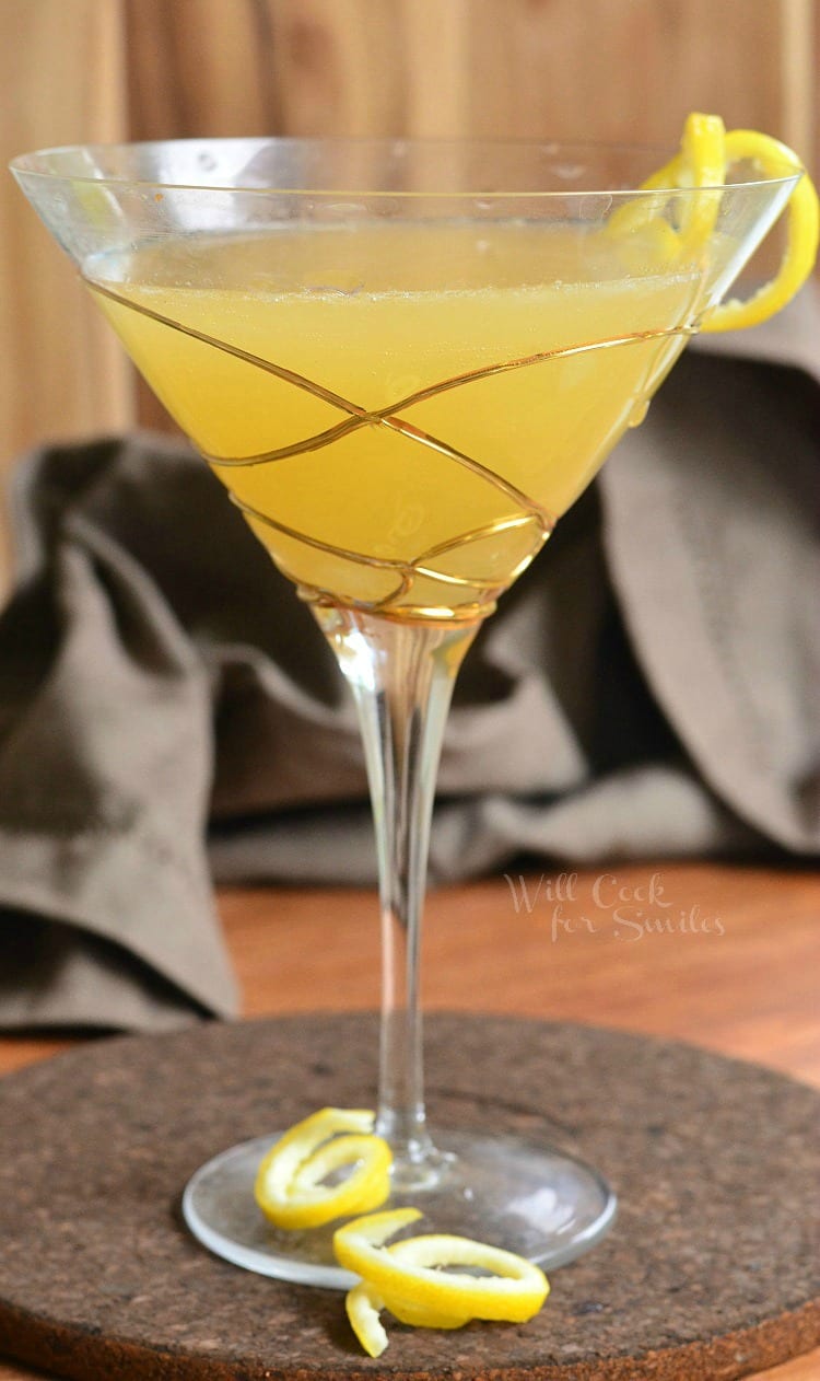 Pineapple Lemon Martini in a martini glass with a lemon peel twist as garnish sitting on a table 