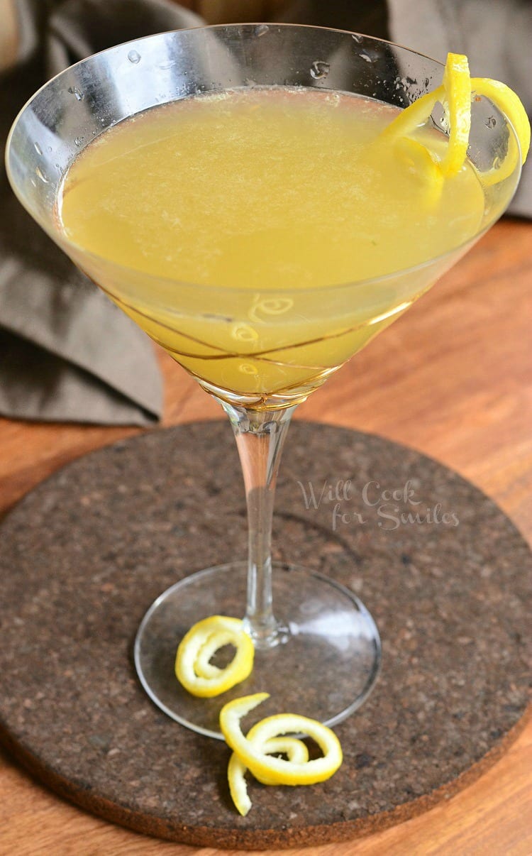 Pineapple Lemon Martini in a martini glass with a lemon peel twist as garnish sitting on a table 