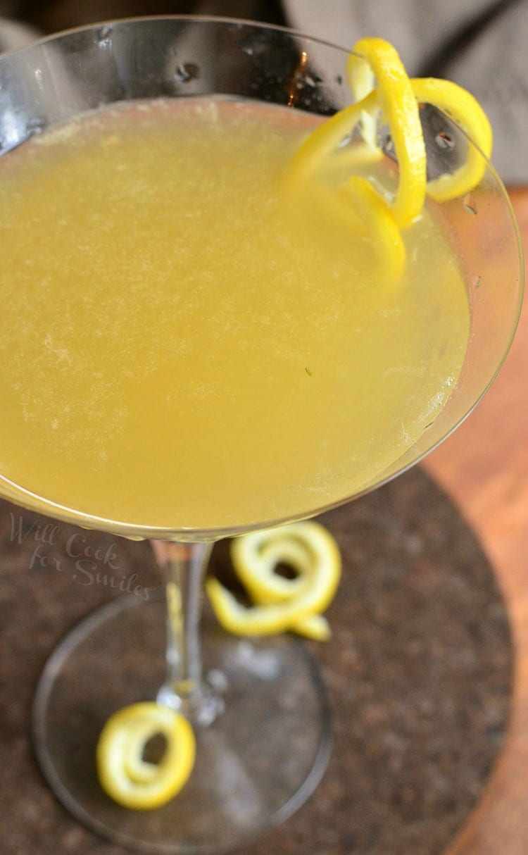 top view Pineapple Lemon Martini in a martini glass with a lemon peel twist as garnish sitting on a table 