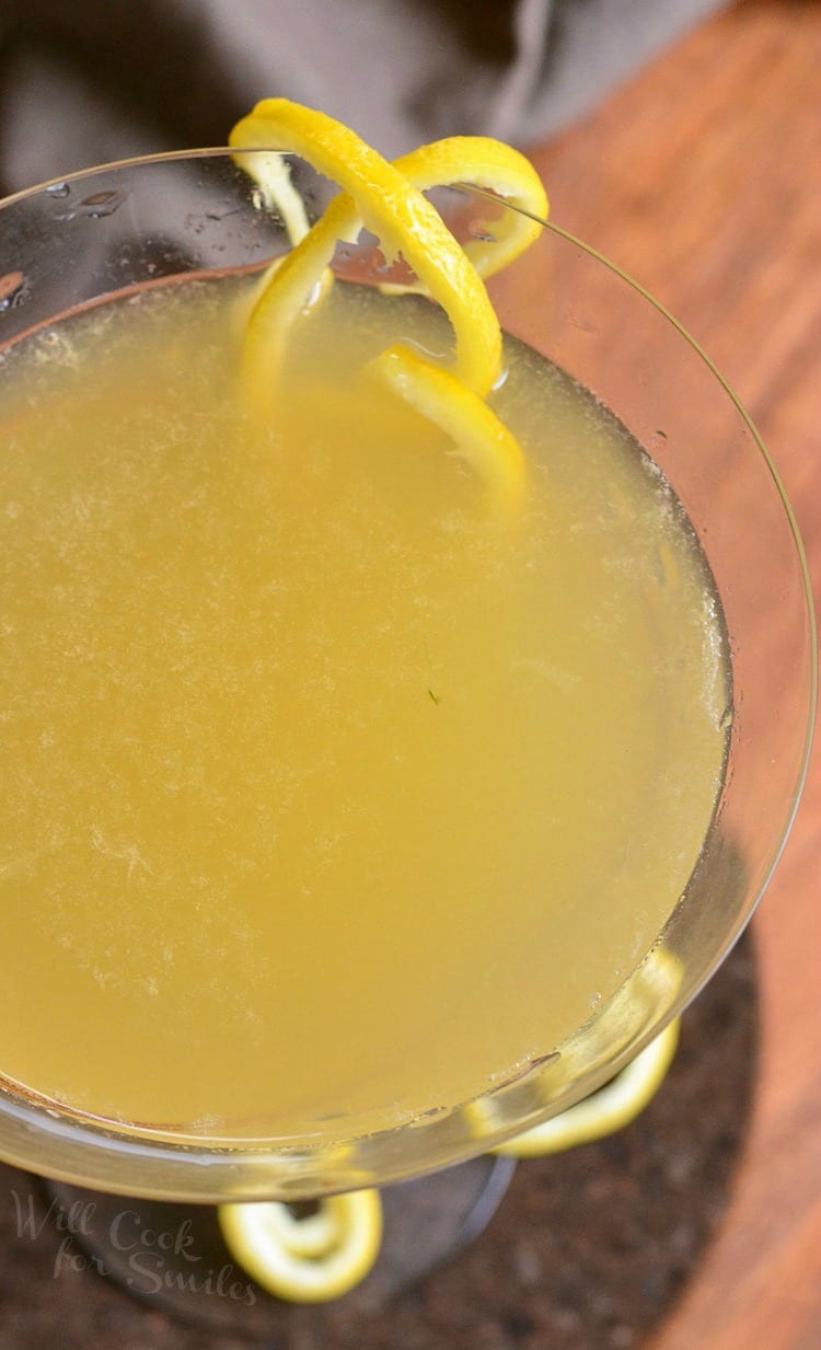 top view close up photo of Pineapple Lemon Martini in a martini glass with a lemon peel twist as garnish sitting on a table 