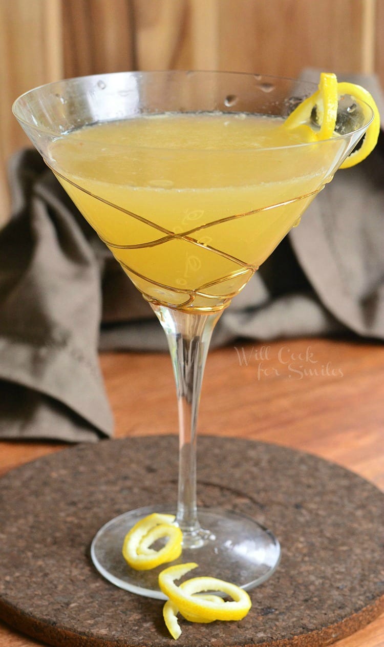 Pineapple Lemon Martini in a martini glass with gold swirls on the glass and lemon peel as garnish 