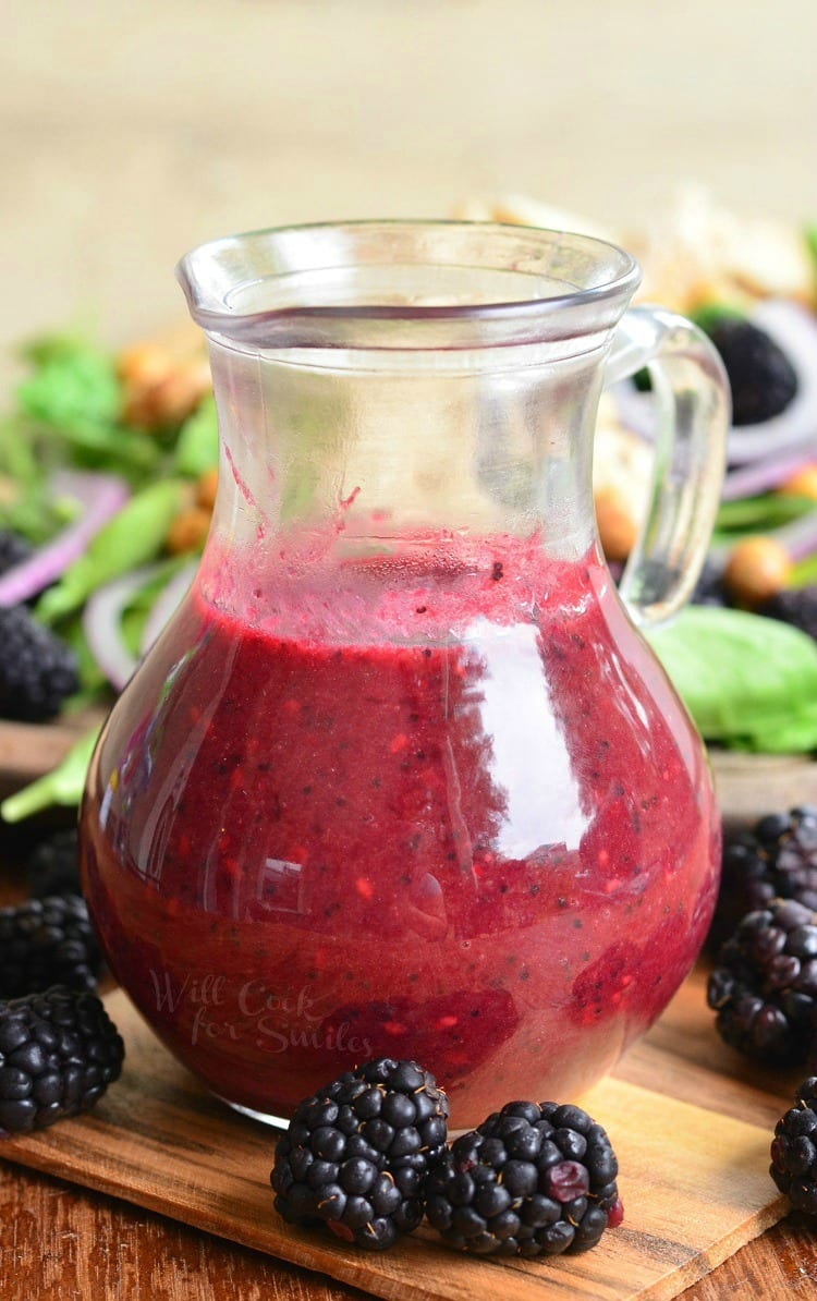Blackberry Poppy Seed Vinaigrette in a glass container with blackberries around it on a cutting board 