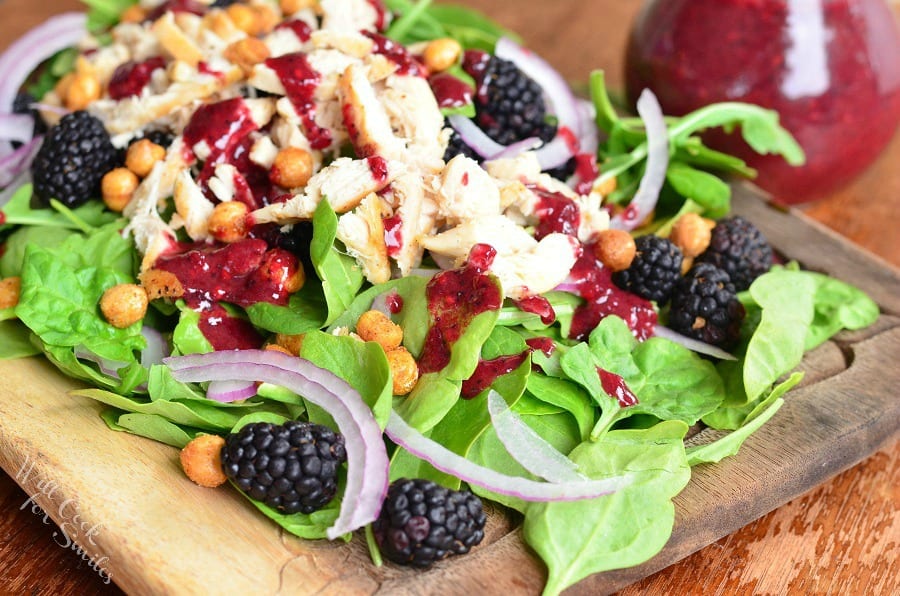 Blackberry Chicken Spinach Salad with Blackberry Poppy Seed Vinaigrette, blackberries, chickpeas, and red onions with salad dressing in the background 