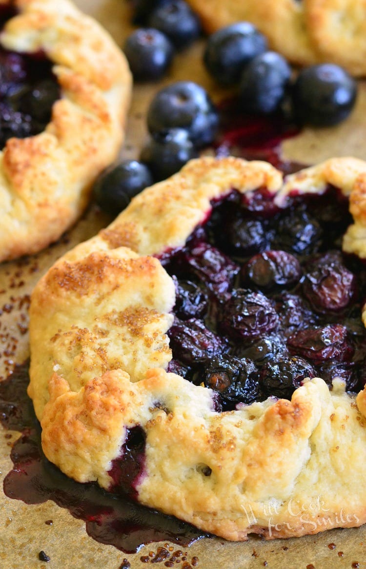 Blueberry Vanilla Lemon Galette on parchment paper with blueberries around it 