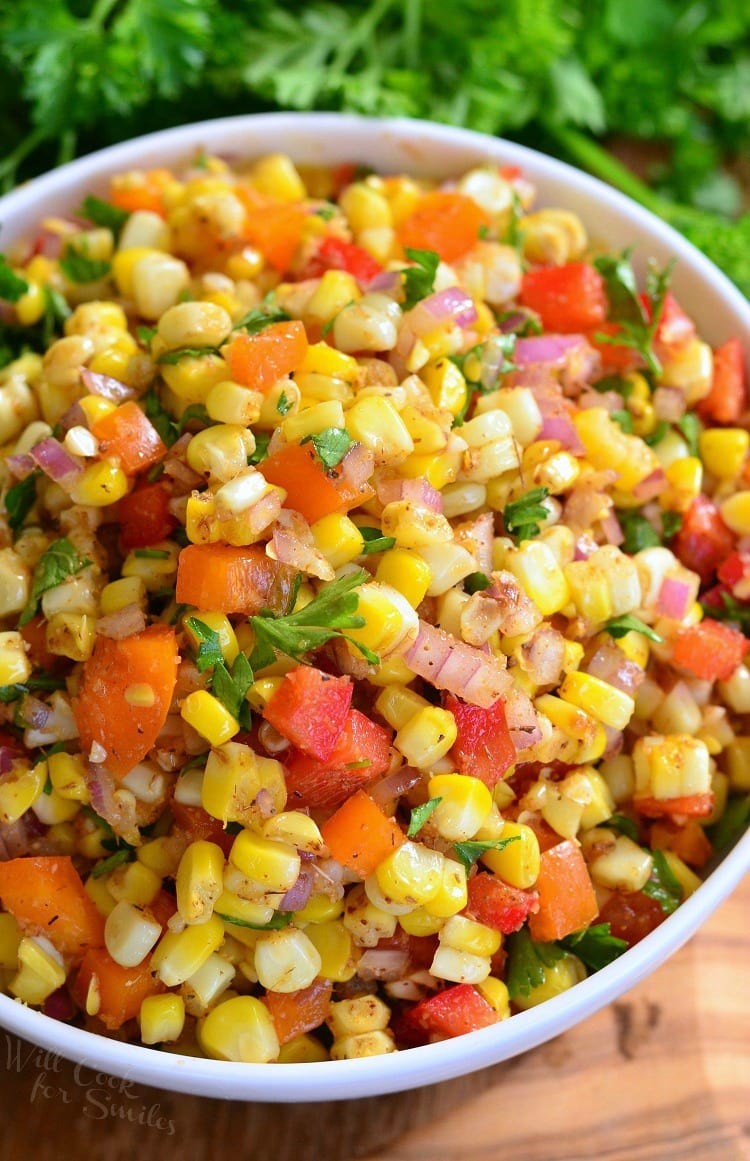 top view photo of Cajun Corn Salad with corn, red and orange bell peppers, red onion, an cilantro in a white bowl
