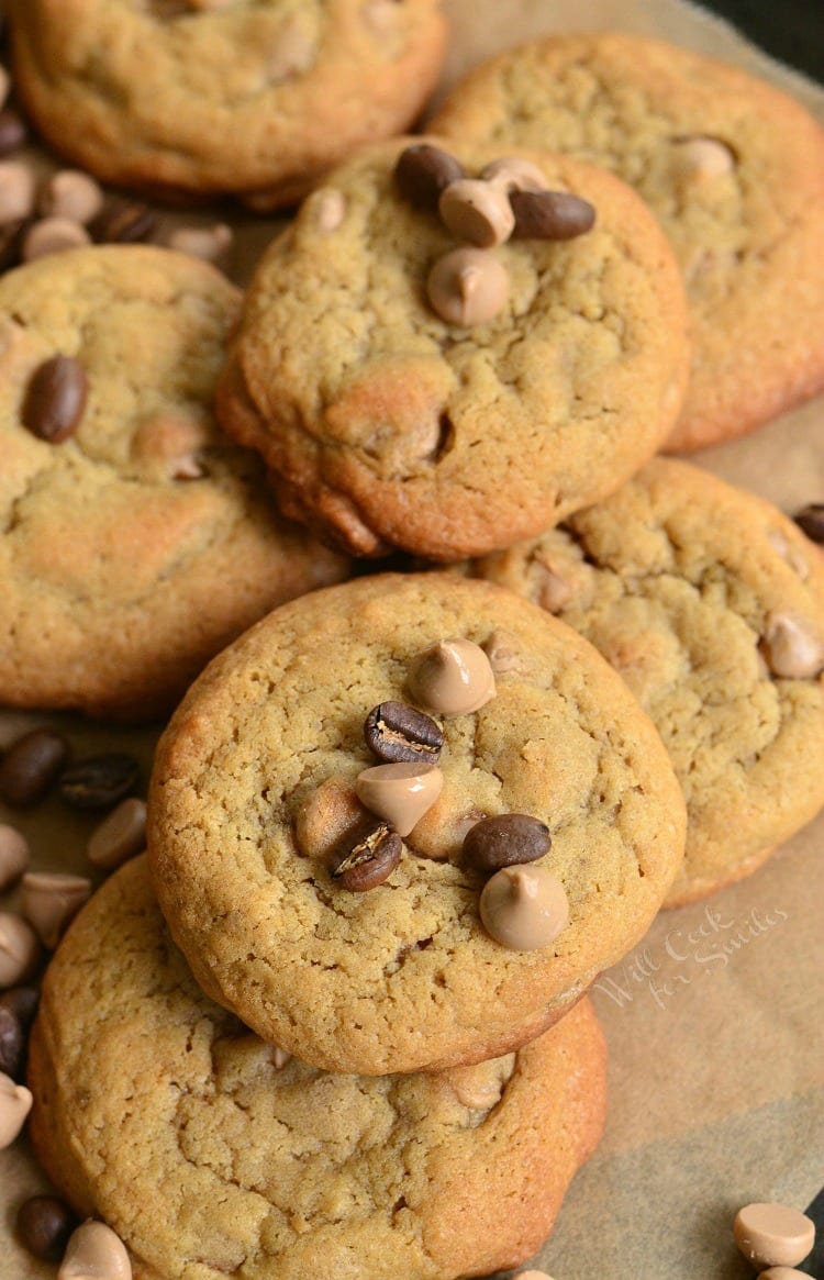 Cappuccino Cookies stacked up on parchment paper with chocolate chips and cappuccino chips around it and ontop 