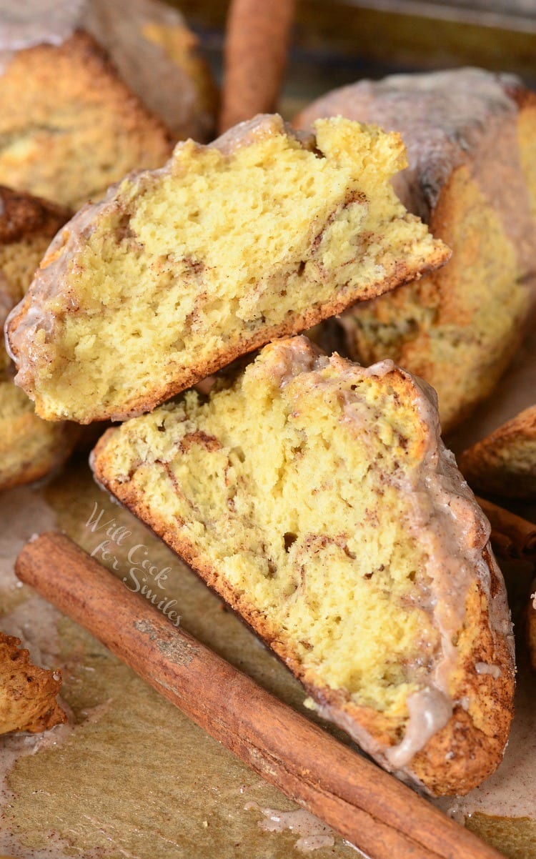 Glazed Cinnamon Swirled Scones on parchment paper with cinnamon sticks around it 