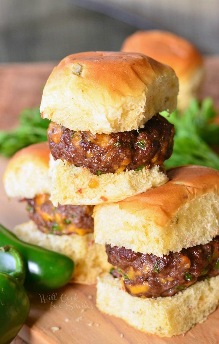 Jalapeno Cheddar Sliders on a bun stacked up on a wood table 