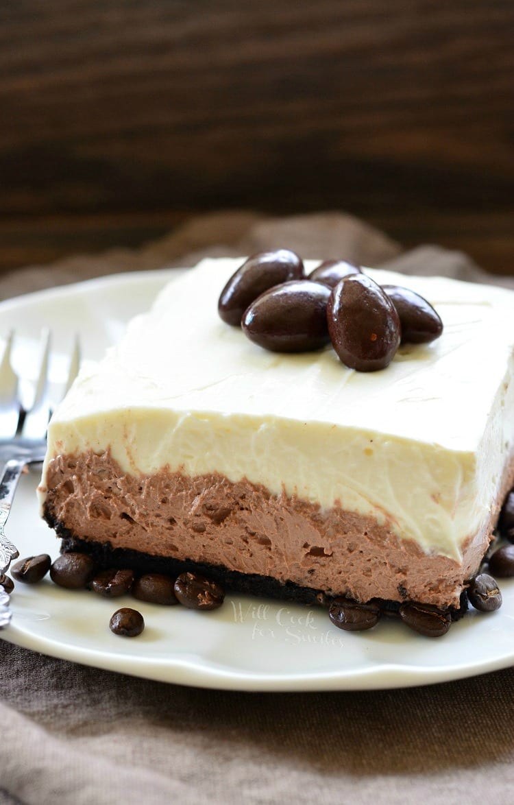 Layered Chocolate Espresso Cheesecake Dessert with chocolate covered expresso beans on top on a white plate 