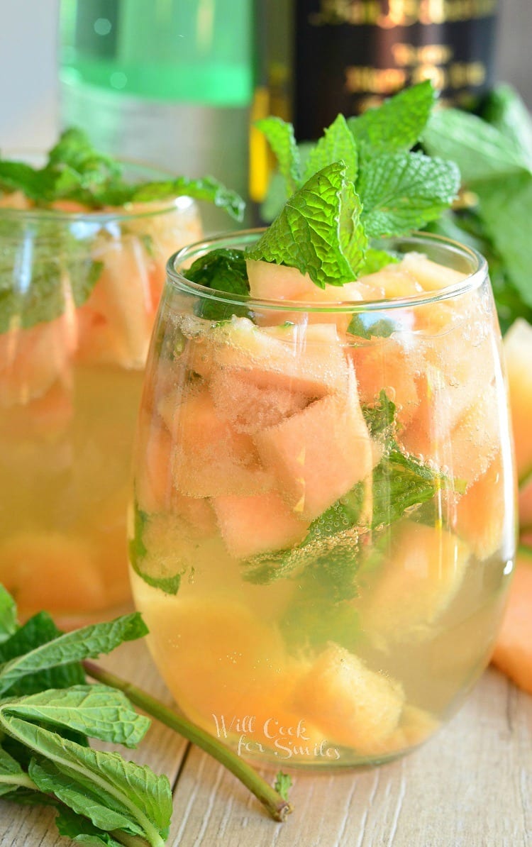 Melon Mint Wine Spritzer with cantaloupe and mint in a stemless wine glass with mint on top as a garnish