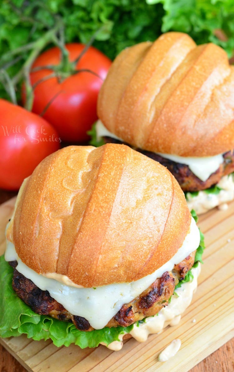 Top view of Chicken Burger with cheese on a bun with lettuce and sauce on a wood cutting table 