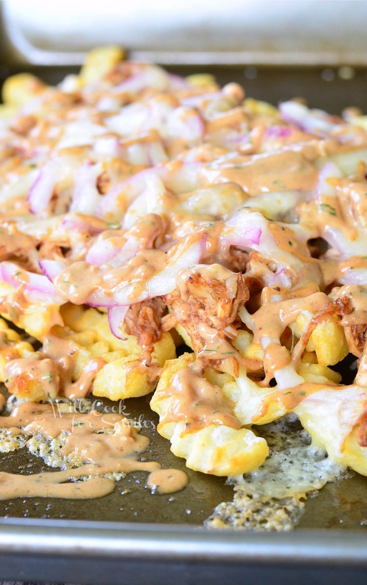 BBQ Ranch Chicken Loaded Fries with chicken, cheese, and red onions on a baking dish 