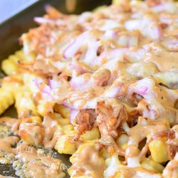 BBQ ranch chicken loaded fries on a baking tray loaded with toppings