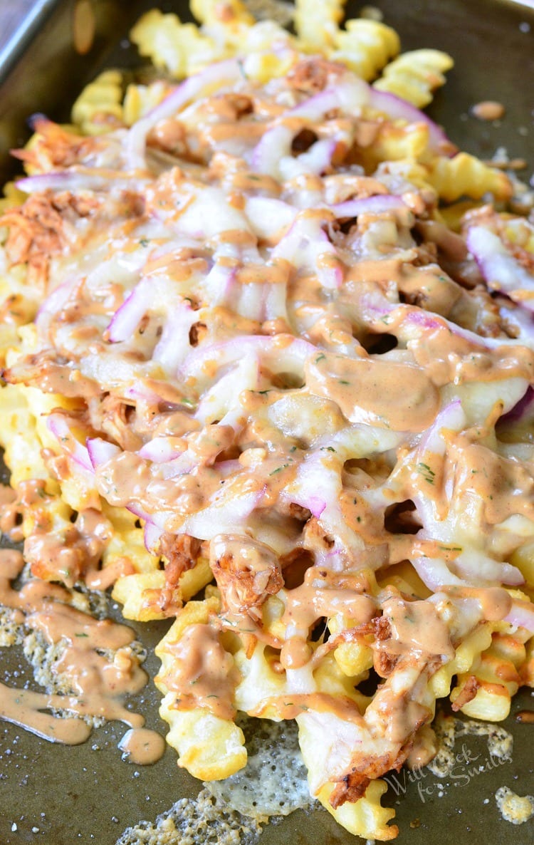 BBQ Ranch Chicken Loaded Fries with chicken, cheese, and red onions on a baking dish 
