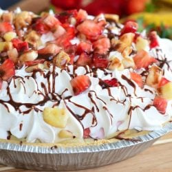 Banana Split Ice Cream Pie on a wooden table with bananas and strawberries in the background as viewed close up