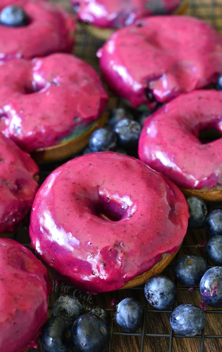 Blueberry Doughnuts with Blueberry Cream Whiskey Glaze on a cooling rack on a wood table 