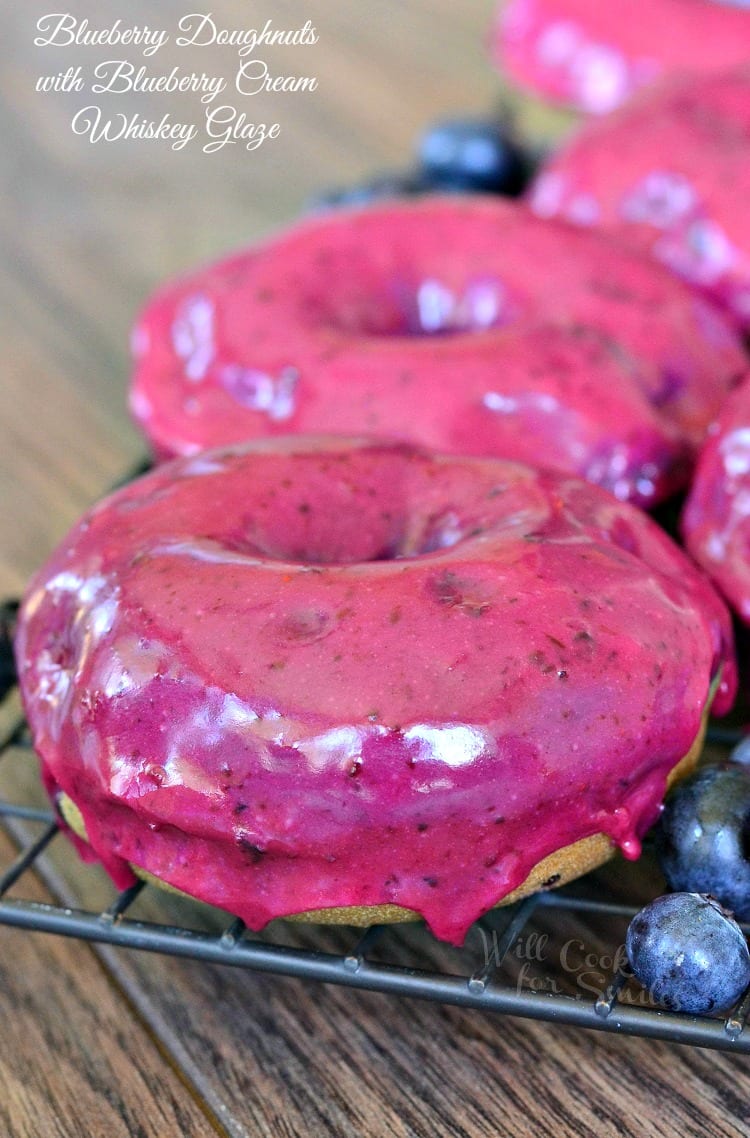 Blueberry Doughnuts with Blueberry Cream Whiskey Glaze on a cooling rack on a wood table 