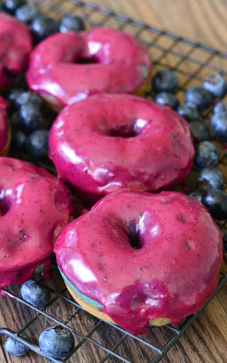 Blueberry Doughnuts with Blueberry Cream Whiskey Glaze on a cooling rack on a wood table 