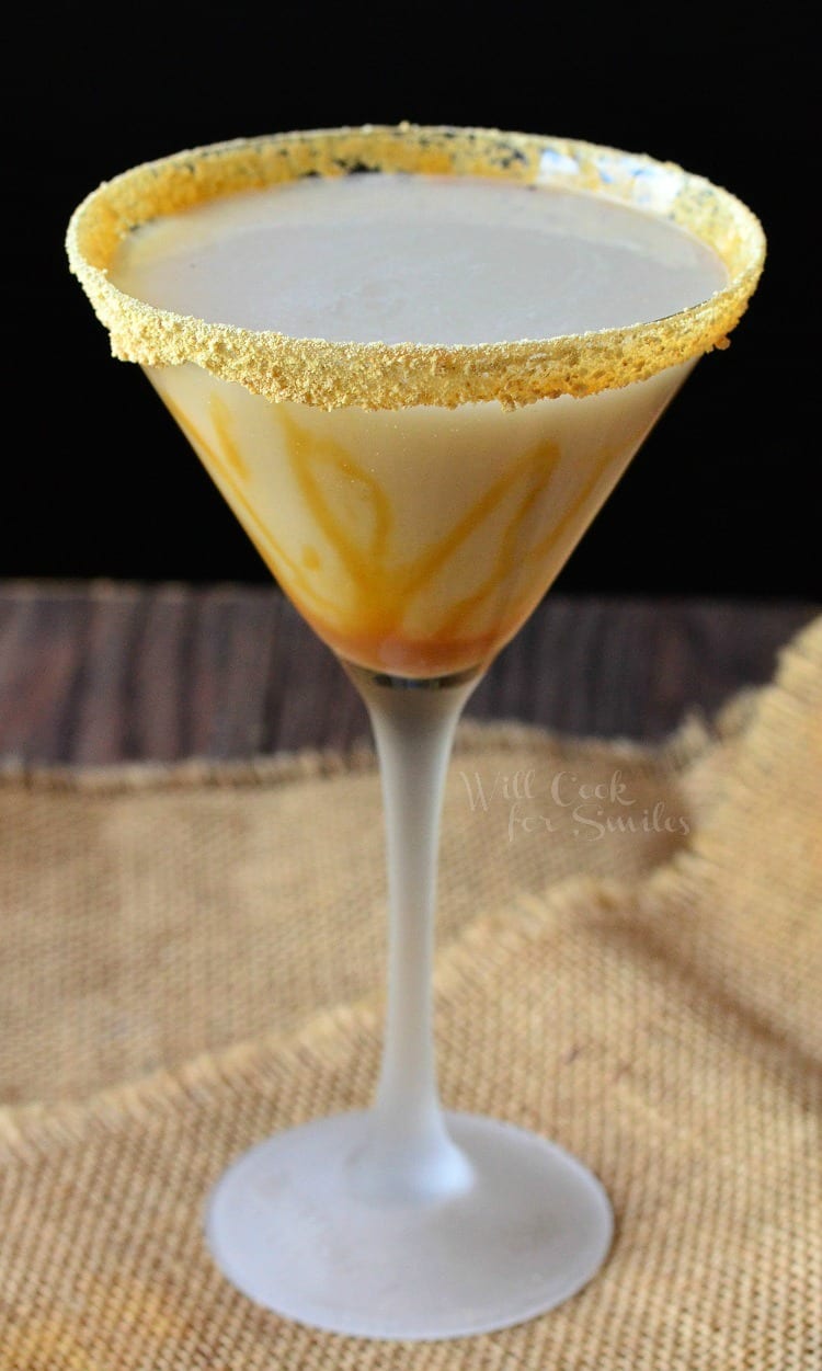 Caramel Cake Martini in a martini glass with caramel topping around the glass sitting on a burlap table cloth 