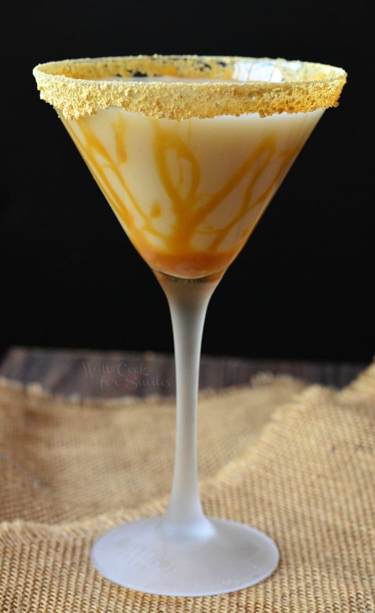 Caramel Cake Martini in a martini glass with caramel topping around the glass sitting on a burlap table cloth 