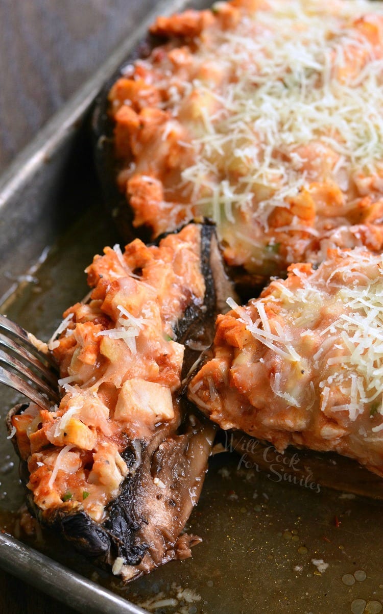 Chicken Parmesan Stuffed Portobello with cheese on top on a baking sheet with a fork in a piece of it