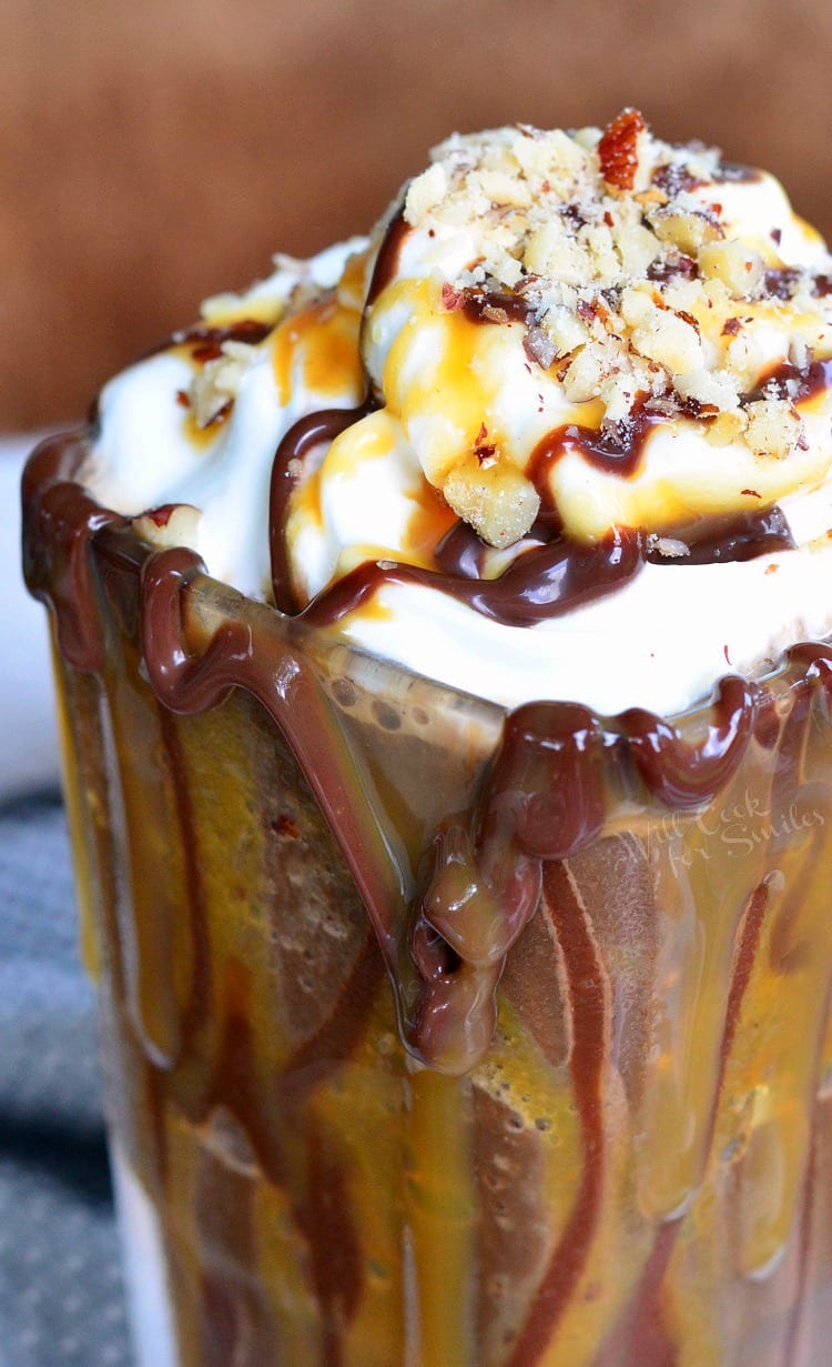 Dessert glass filled with frozen turtle mocha dessert drink topped with turtle crumbs, caramel and fudge as viewed close up and slightly above