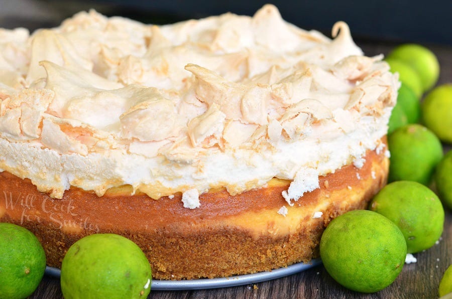 Key Lime Pie Cheesecake with meringue on top on a table with limes 