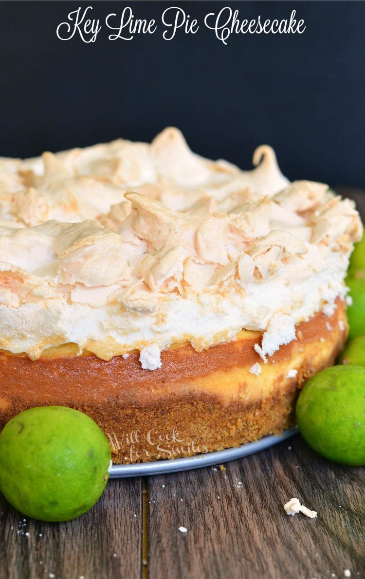 Key Lime Pie Cheesecake with meringue on top on a table with limes 