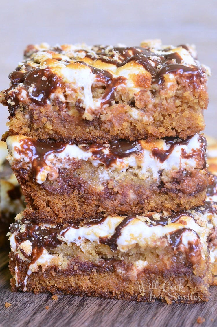  S'Mores Crumble Cookie Bars with melted marshmallows on top stacked up on top of each other 