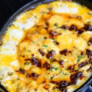 black skillet on a bbq grill with sun-dried tomato and basil mozzarella dip.