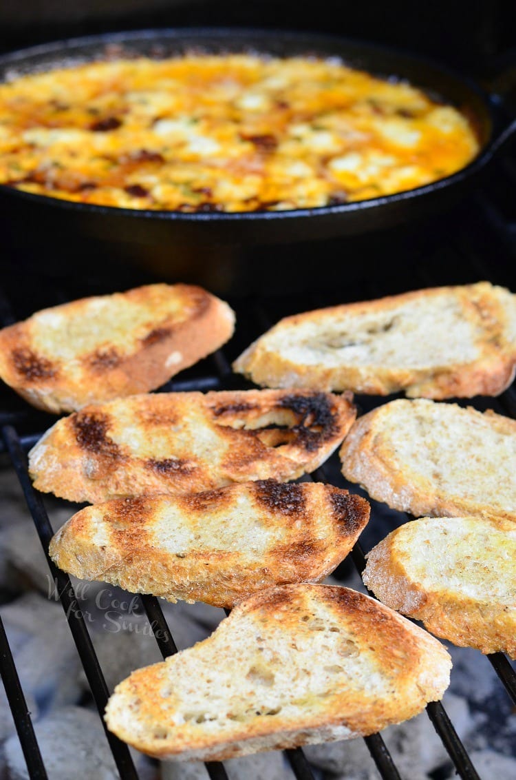 Smokey Sun Dried Tomato in cast iron pan on the grill with slices of bread getting toasted 