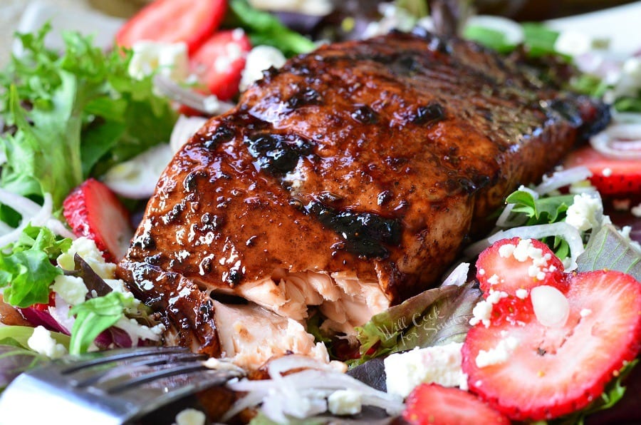 Strawberry Balsamic salad with Glazed Salmon over the top of it with a fork getting a piece of salmon 