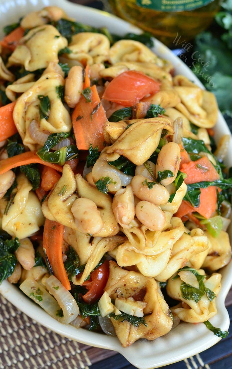 top view photo of Tortellini pasta with carrots, onions, tomato in a yellow bowl 