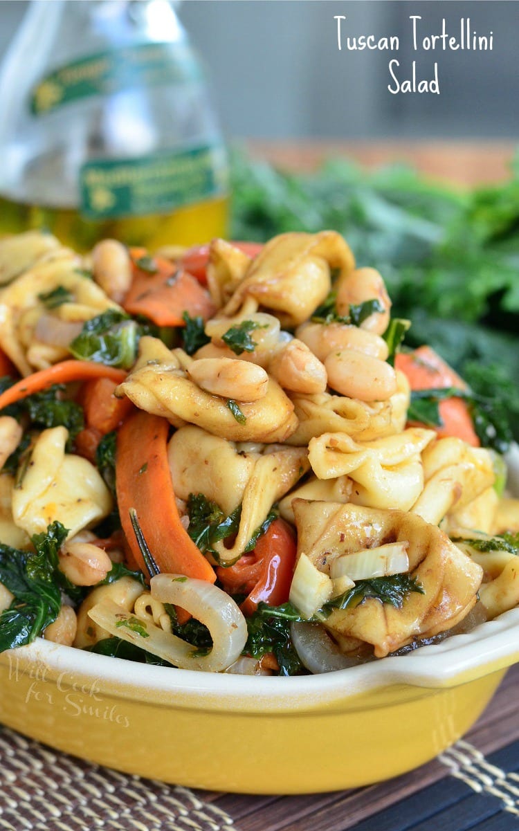 Tortellini pasta with carrots, onions, tomato in a yellow bowl 