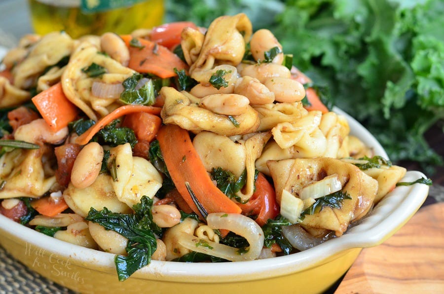 Tortellini pasta with carrots, onions, tomato in a yellow bowl 