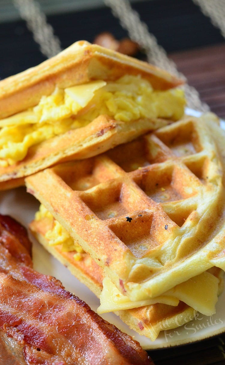 Waffle Breakfast Sandwich with Savory Bacon Waffles with eggs, cheese, and bacon to the left on a white plate  