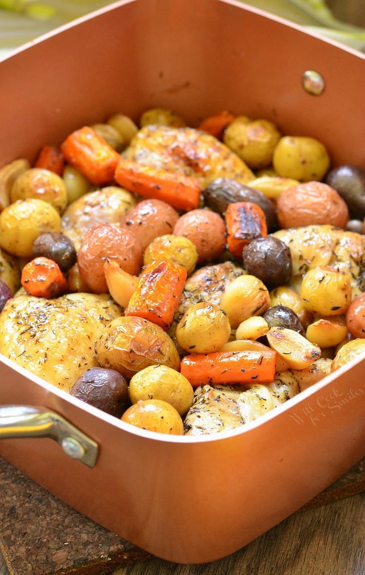 Chicken Drumsticks, garlic, potatoes, and carrots in a pan