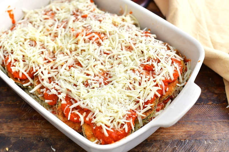 eggplant Parmesan layered in a white casserole with with marinara sauce and shredded mozzarella cheese ready to go into the oven