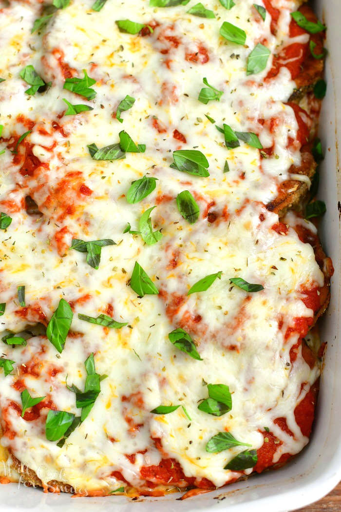 close view of just the baked eggplant Parmesan topped with fresh basil in the baking dish but baking dish not visible